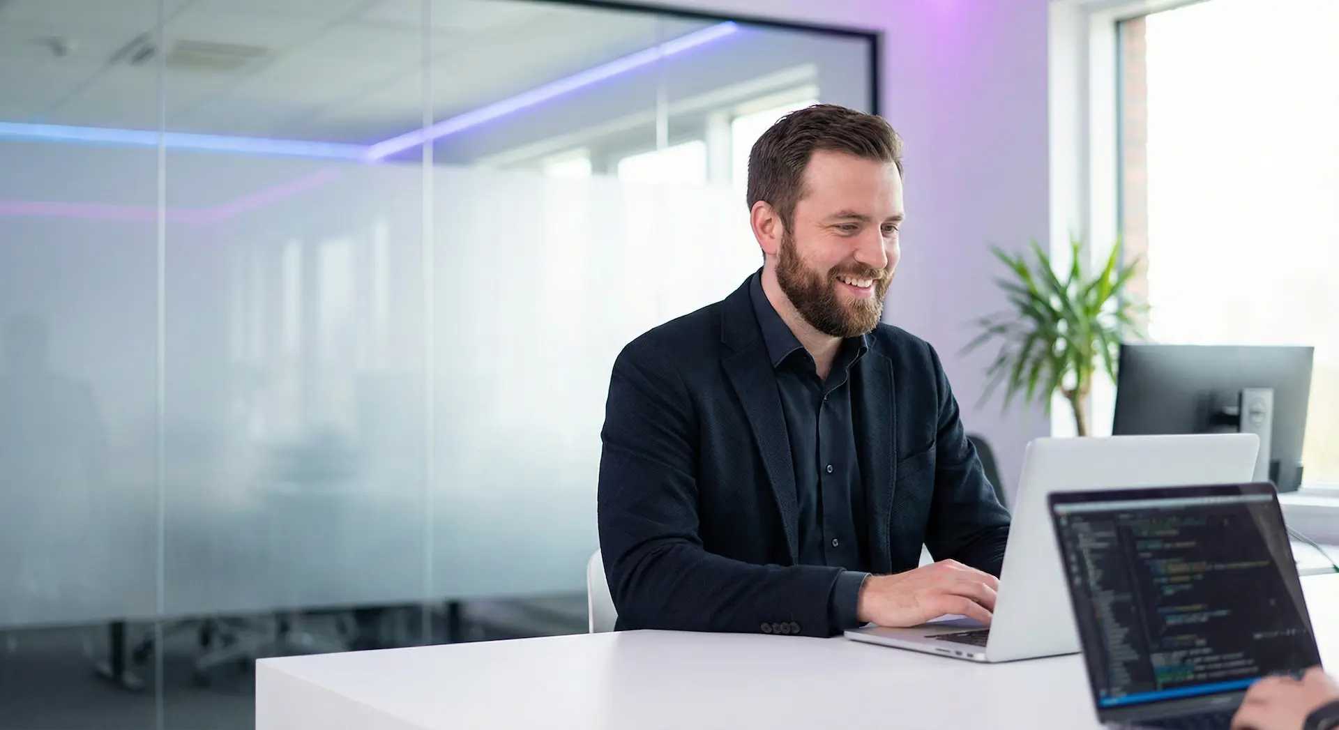 Consultant WordPress professionnel et souriant travaillant sur la création d'un site web moderne sur son ordinateur portable.